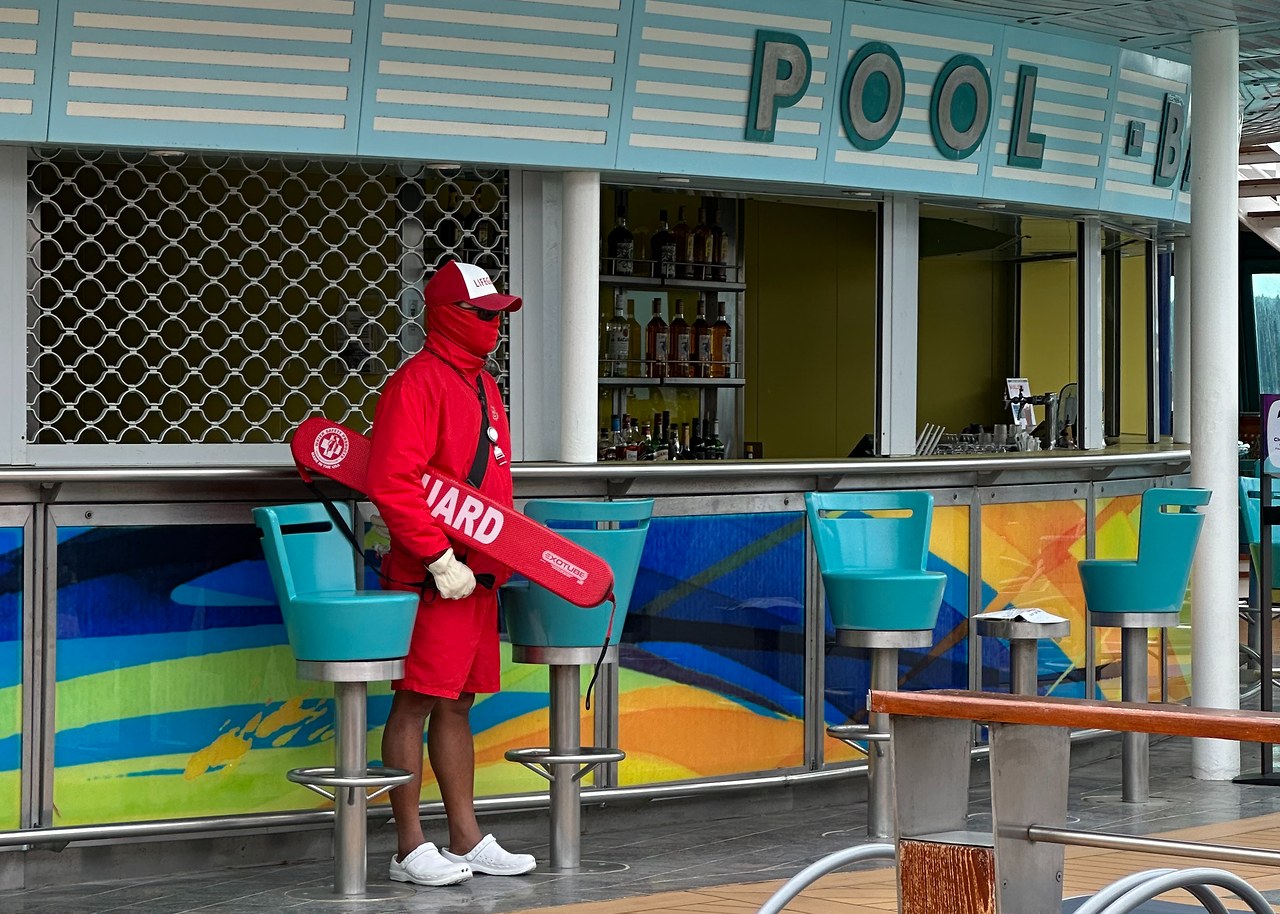 Cruise ship lifeguard bundled up in cold weather near an empty pool deck