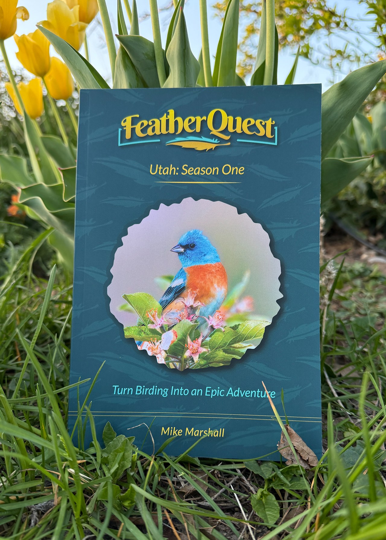 FeatherQuest Utah Season One book standing in spring grass among yellow tulips