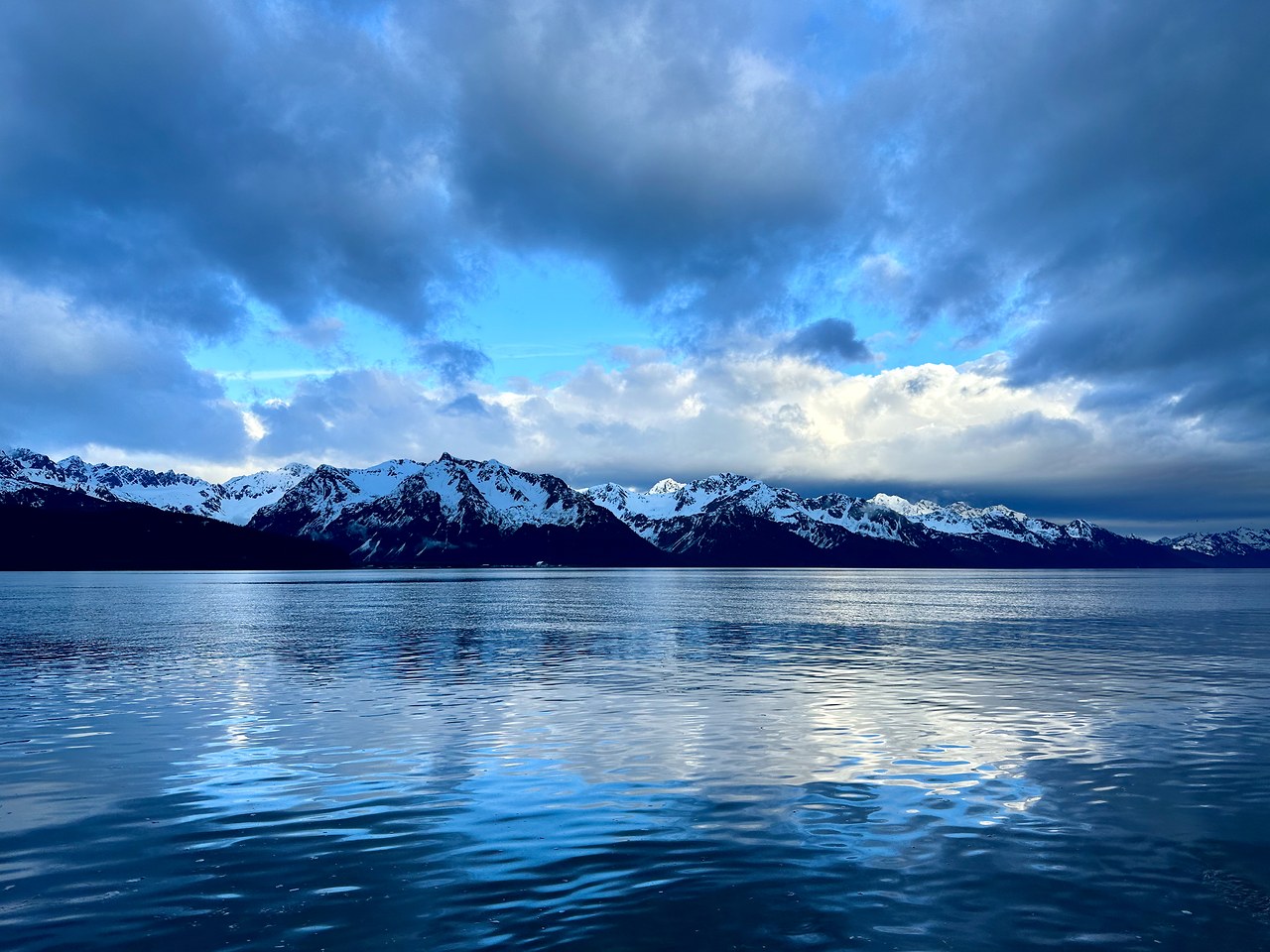 Calm Alaskan water reflecting mountains under soft light