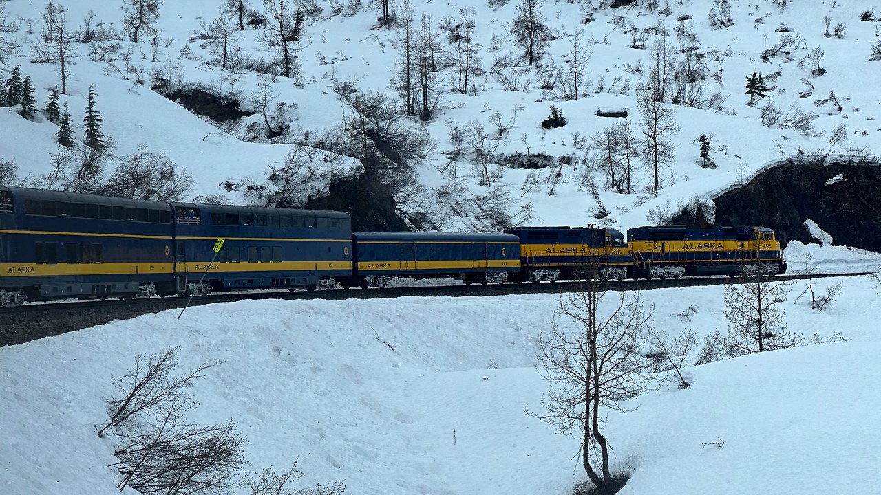 Train winding through snowy Alaskan mountains and forest