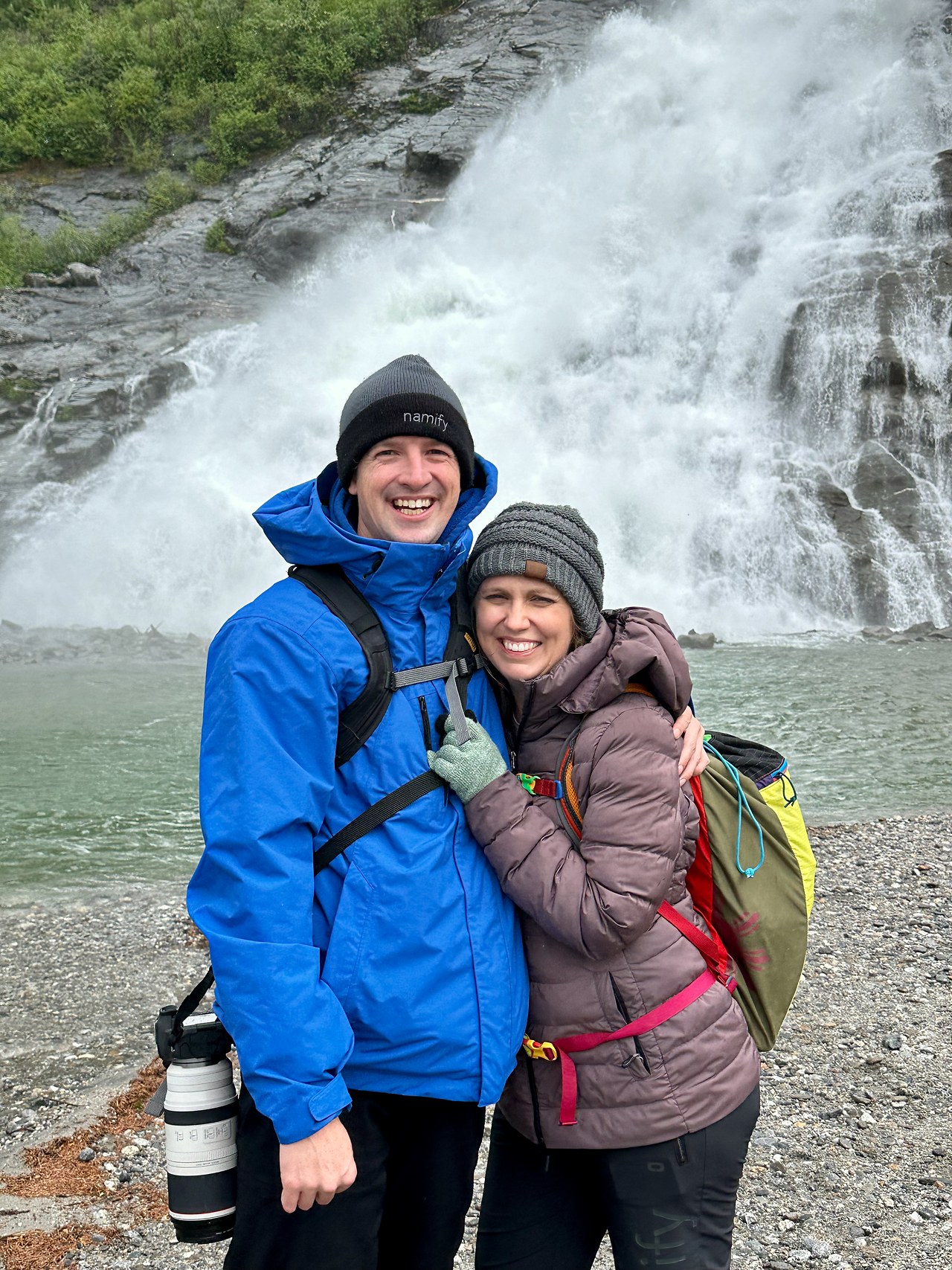 Couple standing together in front of a waterfall in Alaska