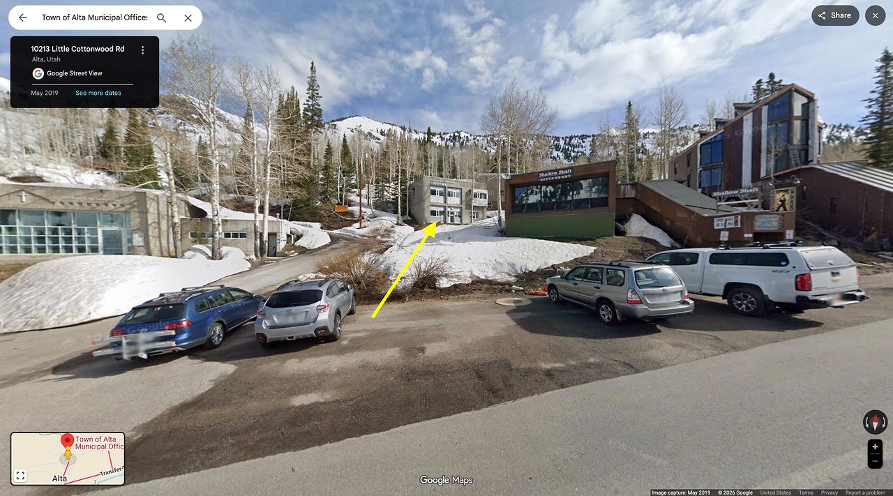 Street view near the Town of Alta municipal buildings at Alta Ski Area with a yellow arrow pointing up the small hill toward the rosy finch feeder area