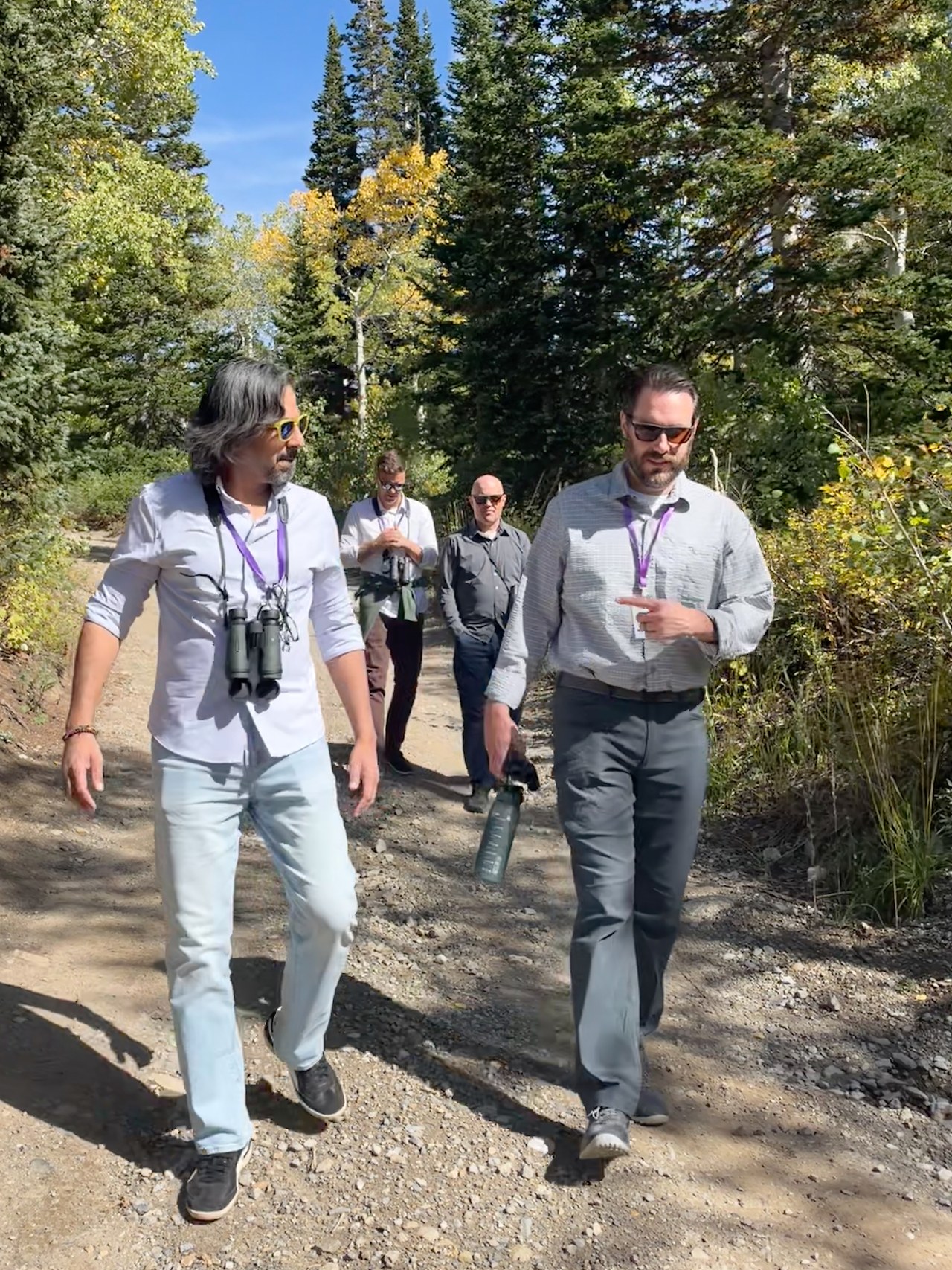 FeatherQuest participants walking with binoculars along a forested trail at Alta, Utah