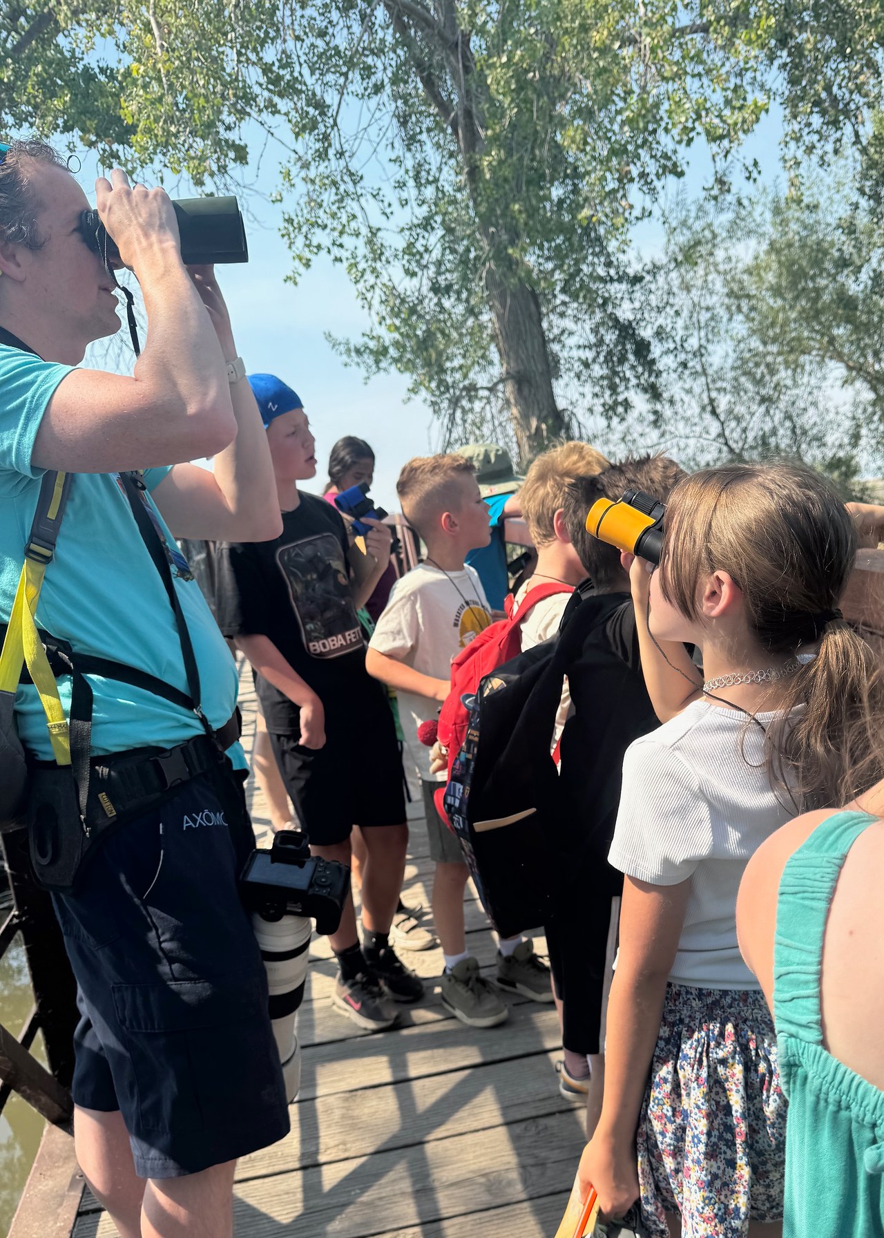 Mike Marshall demonstrates birding with binoculars as Wasatch Nature School campers watch for birds at Utah Lake State Park.