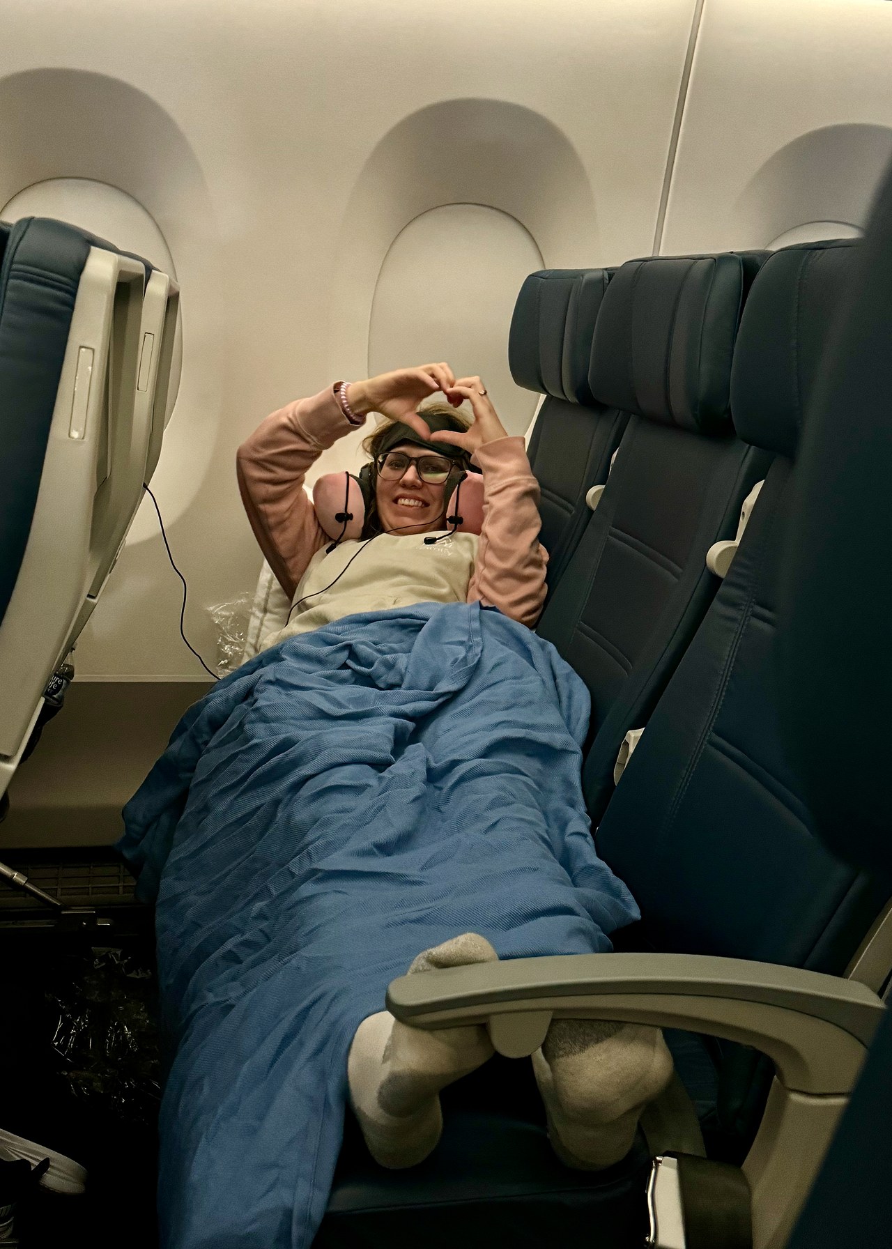 Sleeping across an empty airplane row on the overnight flight to Auckland