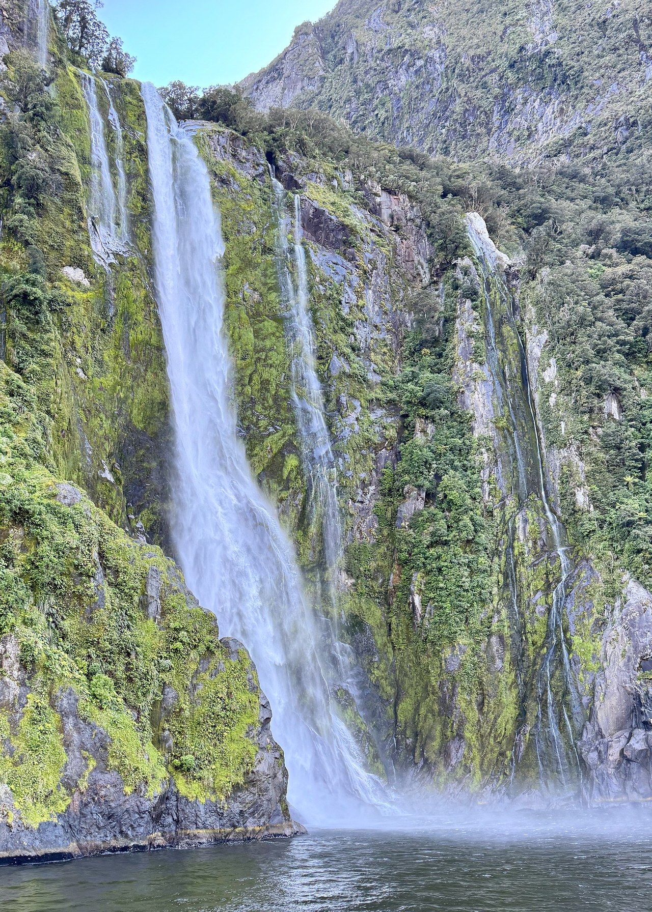 Massive waterfalls flowing down steep cliffs in Milford Sound