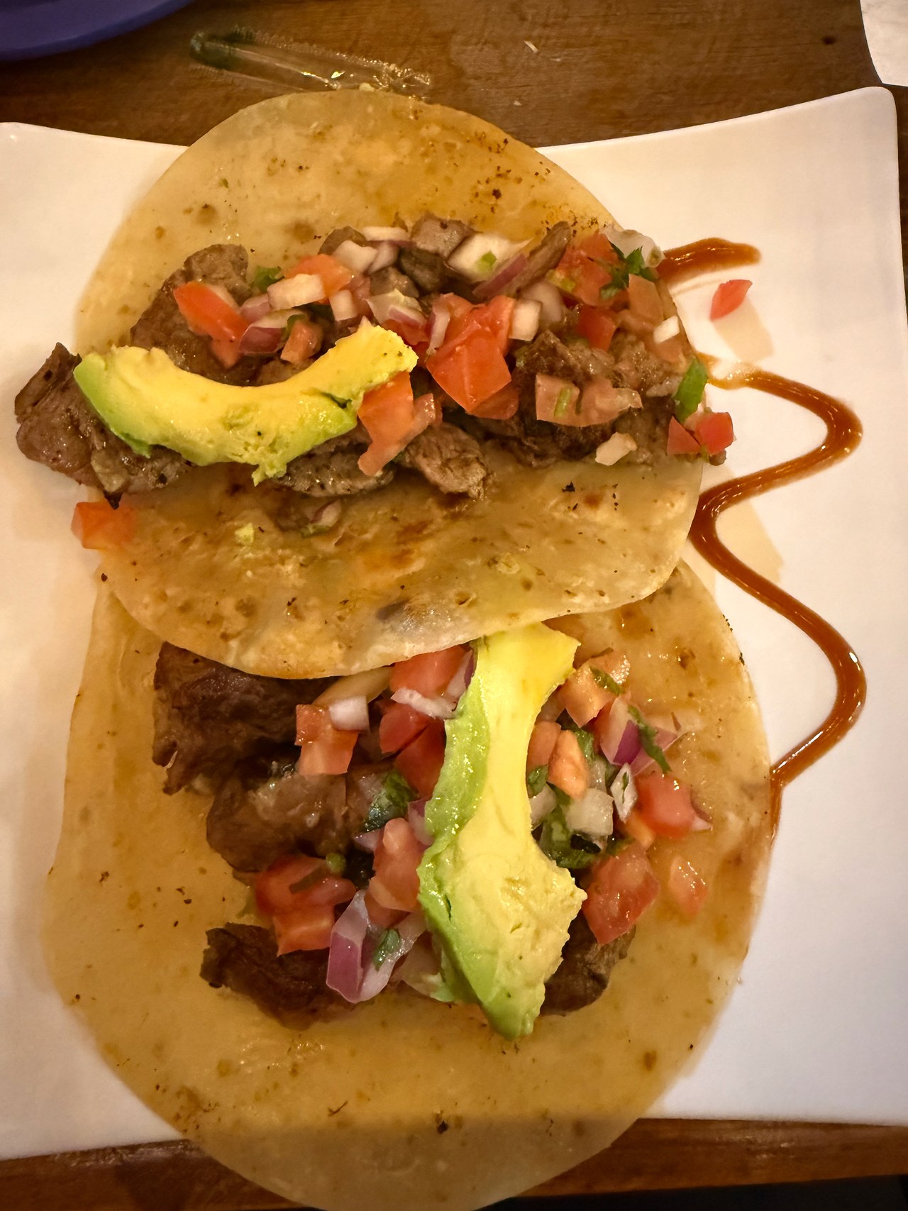 Two steak tacos topped with avocado, tomato, onion, and cilantro at El Cabo Taco in Puerto Peñasco