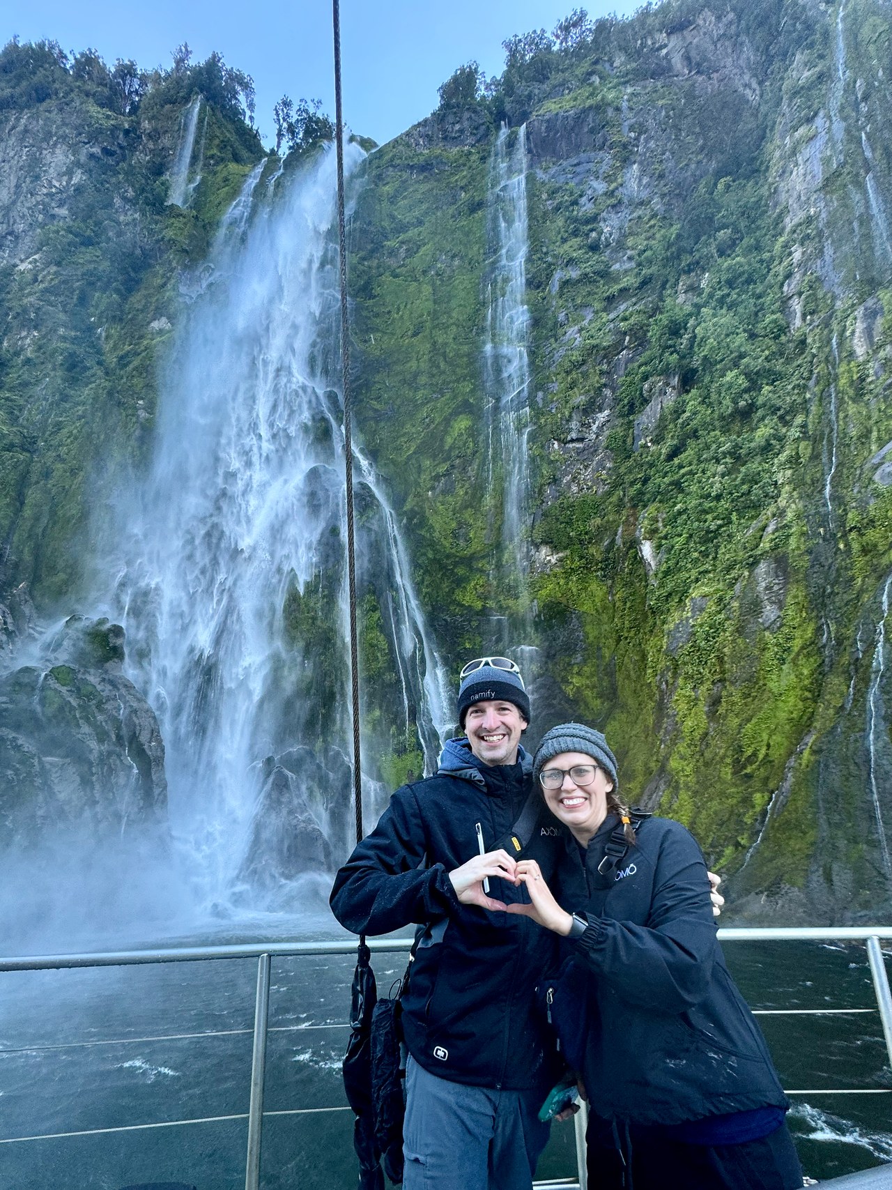 Mike and his wife smiling beside a waterfall in Milford Sound