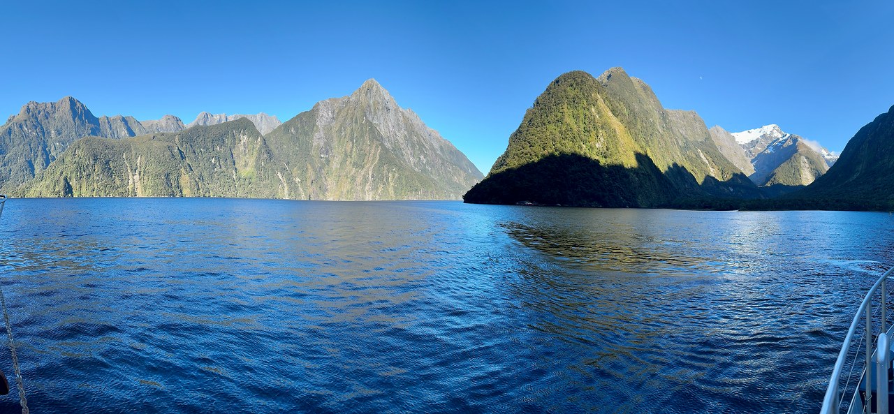 Wide panoramic view of Milford Sound under blue skies