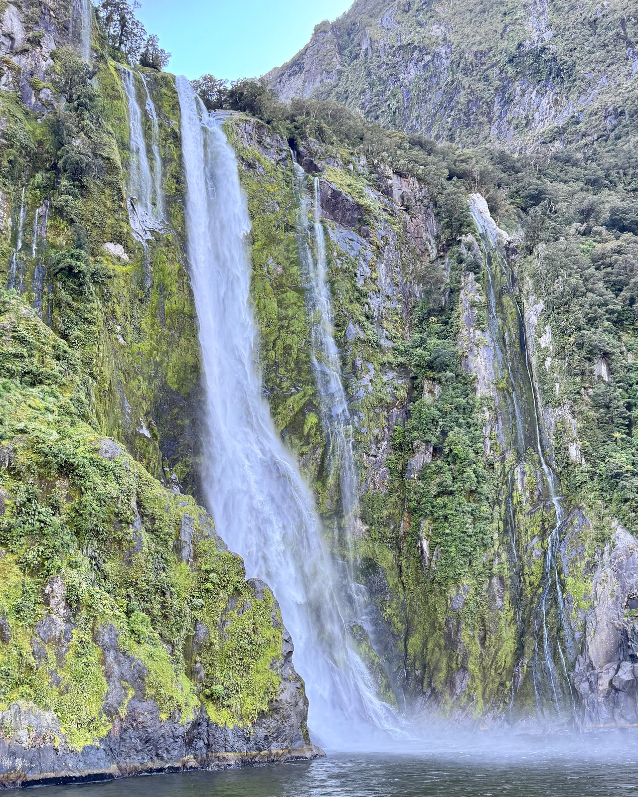 Stirling Falls, also known by the Māori name Wai Manu, crashing into Milford Sound beside the cruise ship