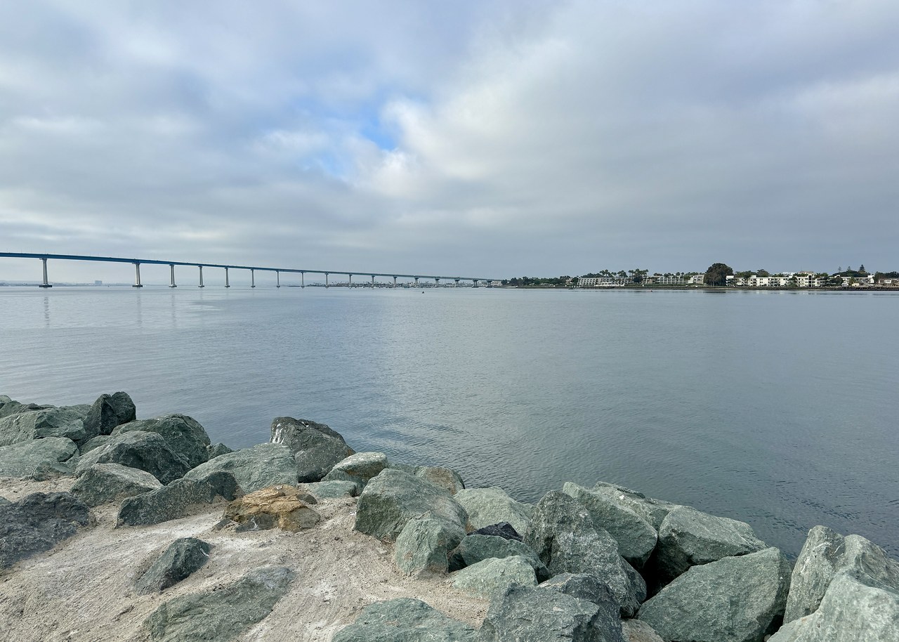 Seaport Village marina with rocks, water, and bridge in the distance