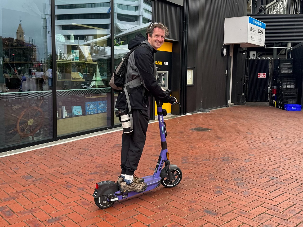 Mike riding a rental electric scooter near the Auckland waterfront on the way to the ferry terminal.