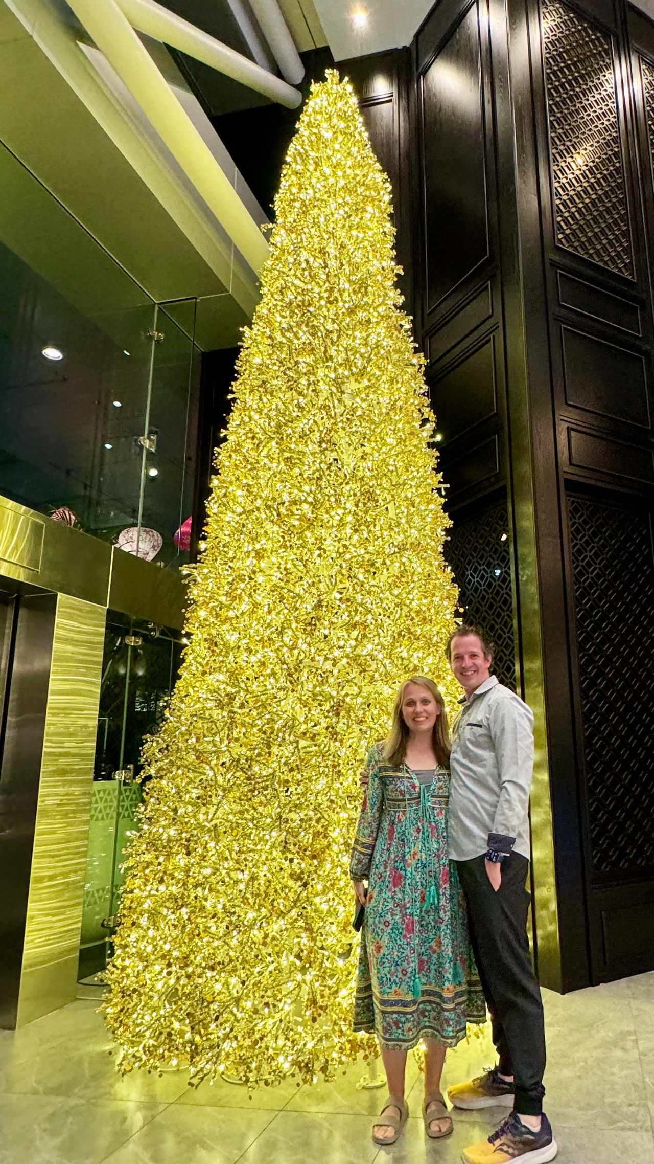Mike and Stacy standing beside a large illuminated Christmas tree inside Auckland's Sky Tower.