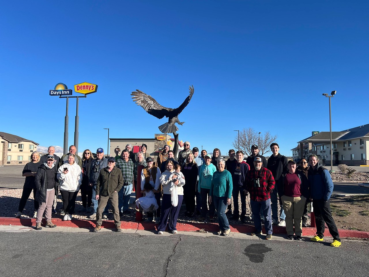 Utah County Birders group photo gathered in Beaver, Utah during the county challenge trip, standing together beneath a large eagle statue at a gas station stop