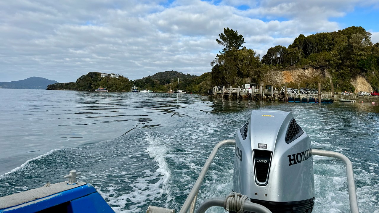 Small water taxi crossing clear water between Stewart Island and Ulva Island