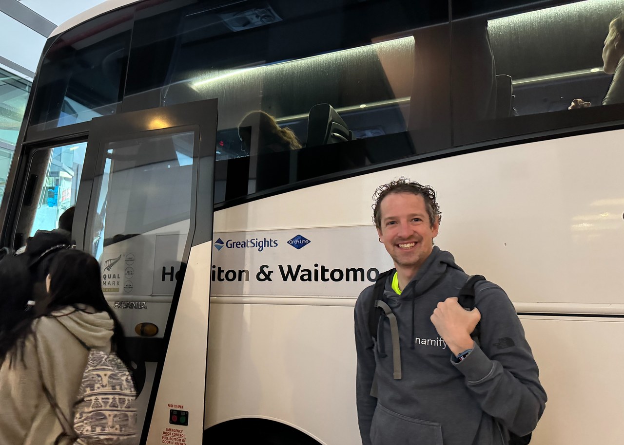 Mike standing beside the GreatSights coach used for a full-day tour from Auckland to Waitomo and Hobbiton.
