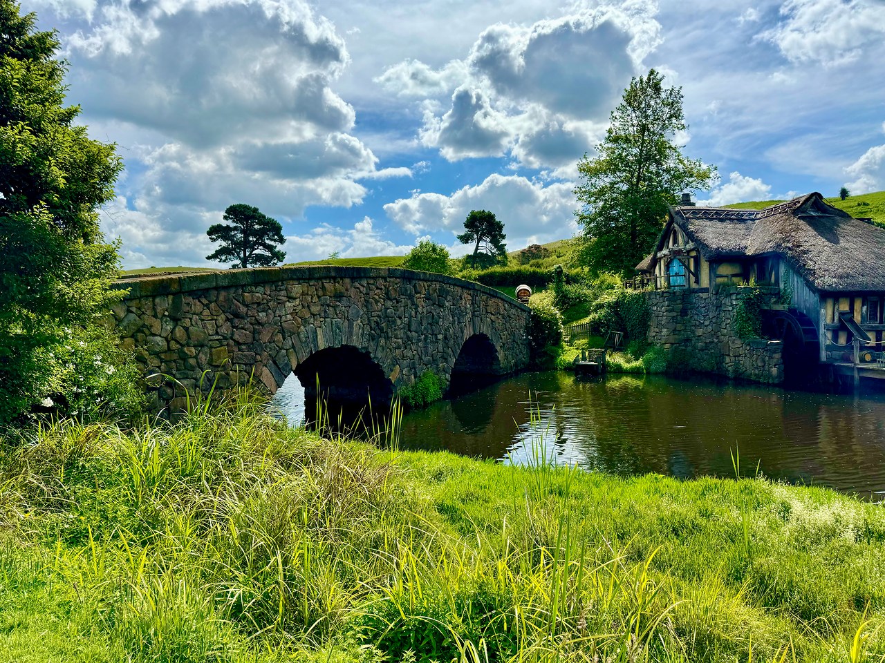 Stone bridge crossing the water toward the Green Dragon Inn at Hobbiton in New Zealand.