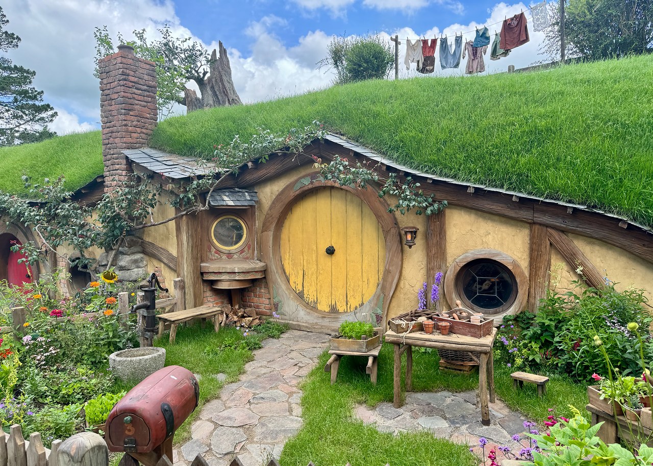 Yellow-doored hobbit hole with laundry and garden details at Hobbiton.
