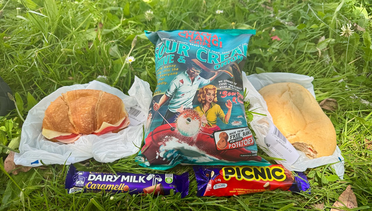 Grocery-store bakery sandwiches, New Zealand chips, and candy bars arranged for a picnic lunch in Wellington.