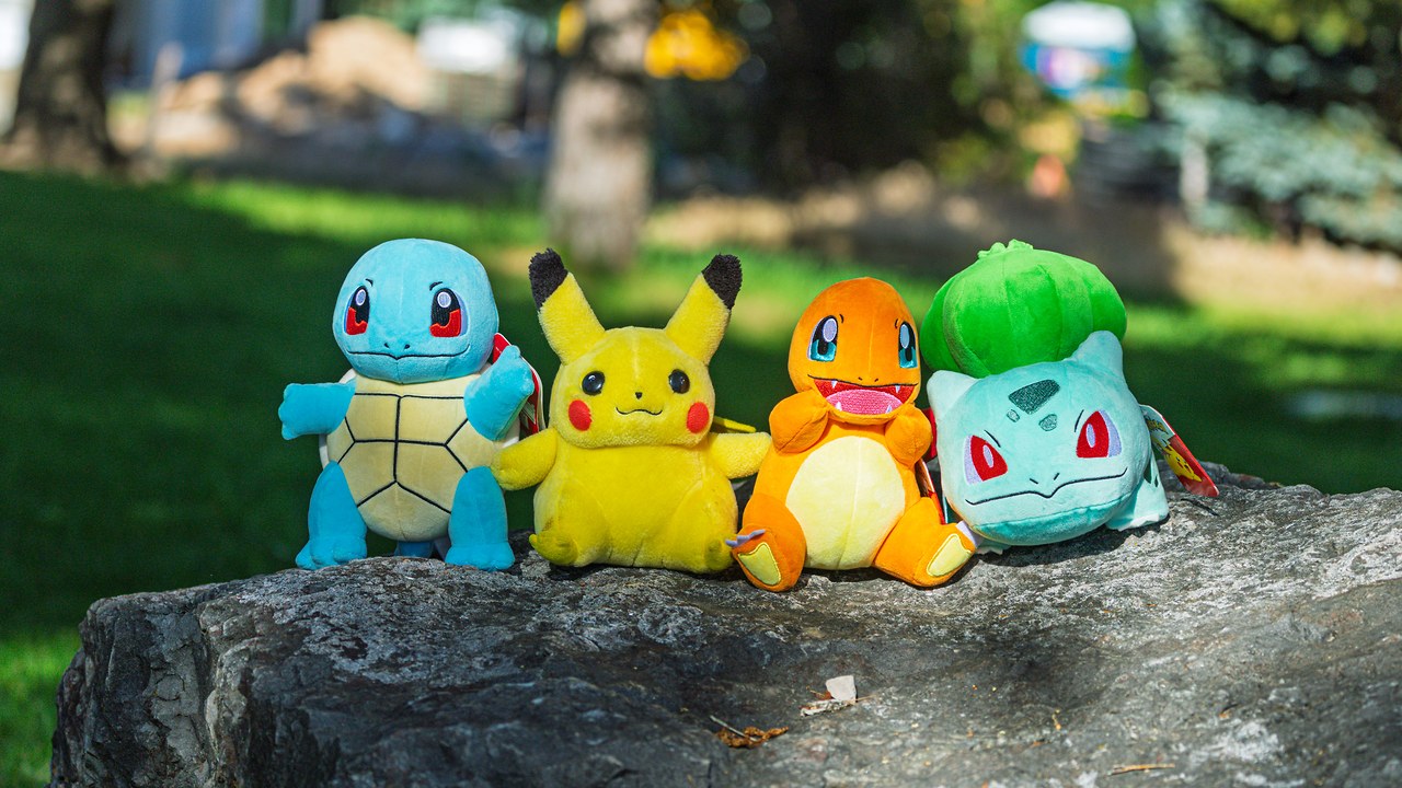 Pikachu, Squirtle, Charmander, and Bulbasaur sitting on a rock outdoors, representing the connection between Pokémon, exploration, discovery, and birding in the real world